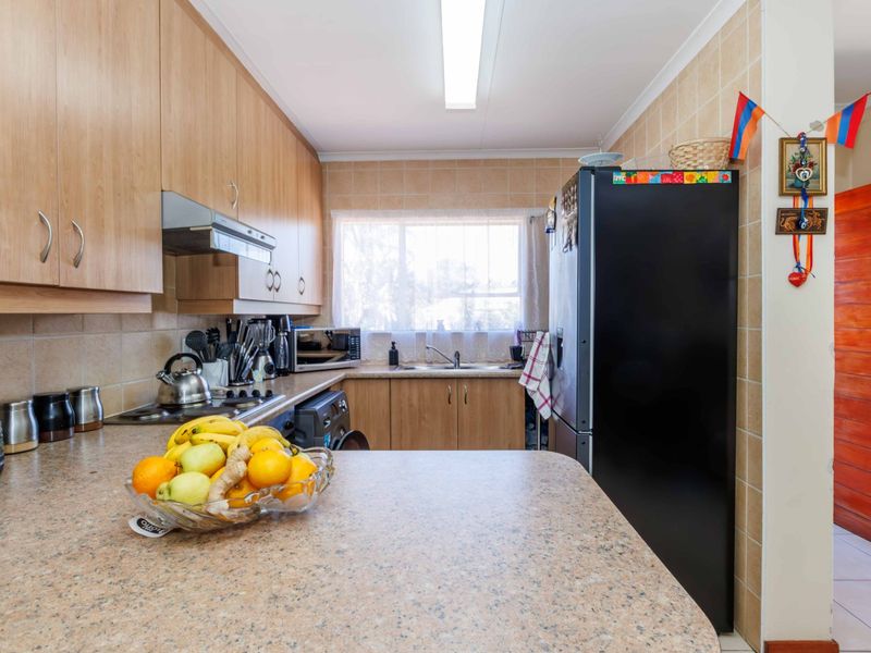 A functional kitchen featuring light wood-tone cabinetry, laminate countertops, tiled splashbacks, and integrated appliances, offering a practical layout for daily meal preparation.