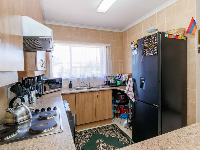 A functional kitchen featuring laminate cabinetry, laminate countertops, a double bowl sink, and an electric hob with an overhead extractor fan.