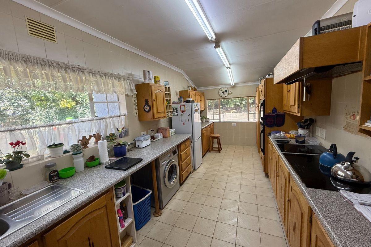 A functional galley-style kitchen featuring traditional wooden cabinetry, laminate countertops, and integrated appliances, offering a practical layout with ample storage space.