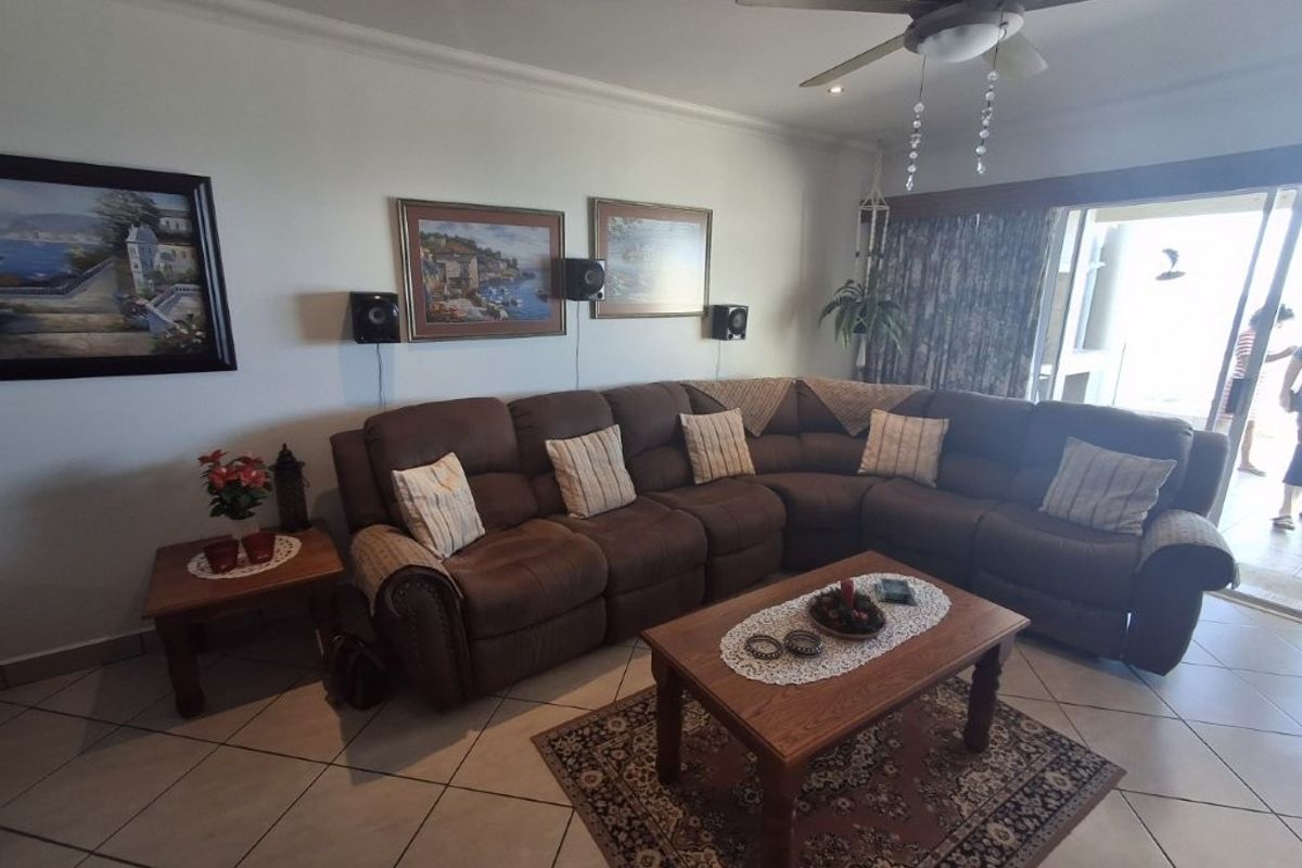 A comfortable living room featuring tiled flooring, a ceiling fan, and large sliding glass doors that provide access to an outdoor area.