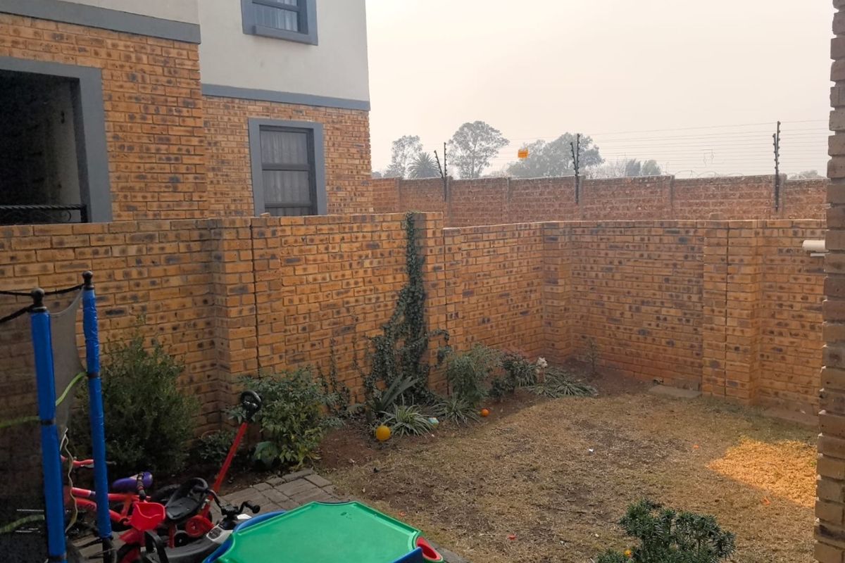 A private rear garden featuring a paved patio area, face brick boundary walls, and integrated electric fencing for added security.