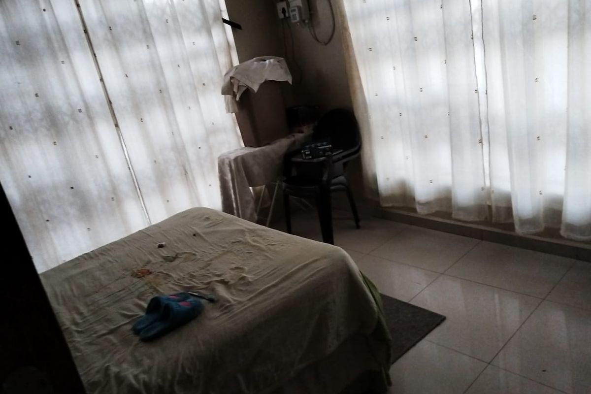 A bedroom featuring tiled flooring and large windows with curtains, providing natural light to the space.