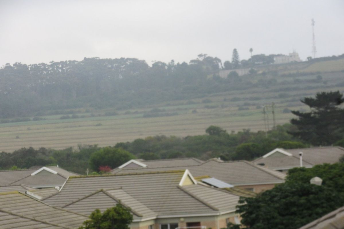 An elevated view overlooking a residential neighborhood with tiled rooftops and a distant landscape.