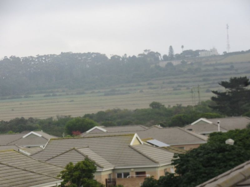 An elevated view overlooking a residential neighborhood with tiled rooftops and a distant landscape.