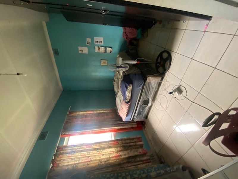 A bedroom featuring tiled flooring and a built-in wardrobe, currently requiring cosmetic updates and maintenance to improve its overall condition.