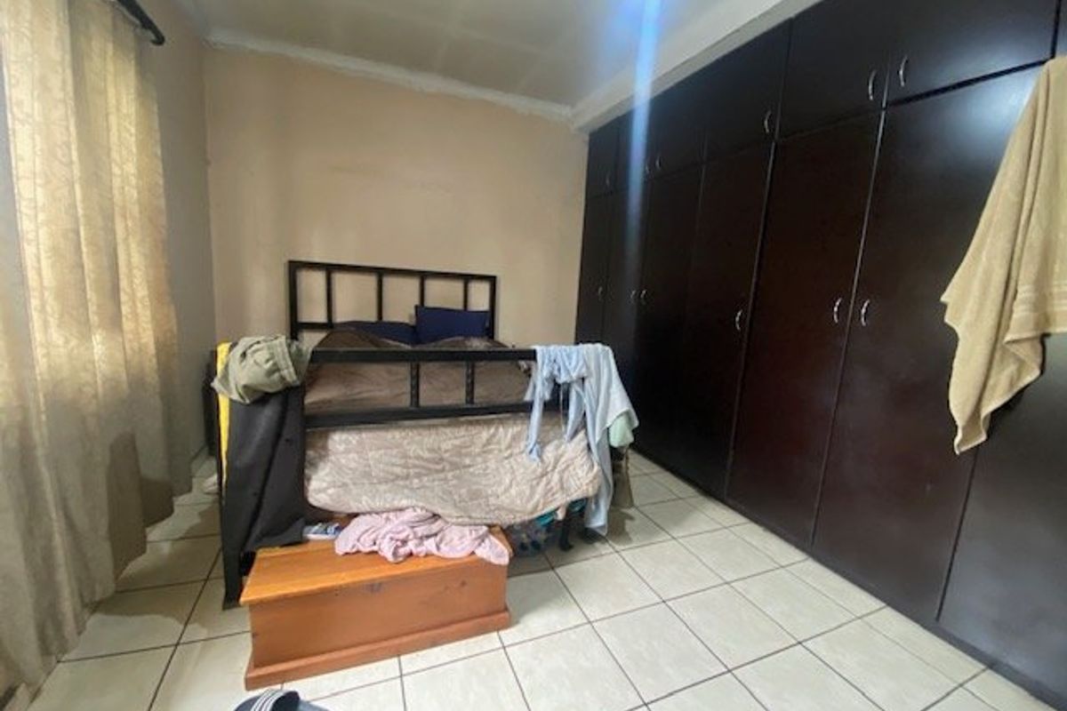 Bedroom featuring dark built-in cupboards and tiled flooring. The room requires cosmetic updates to the walls and ceiling to improve its overall condition.