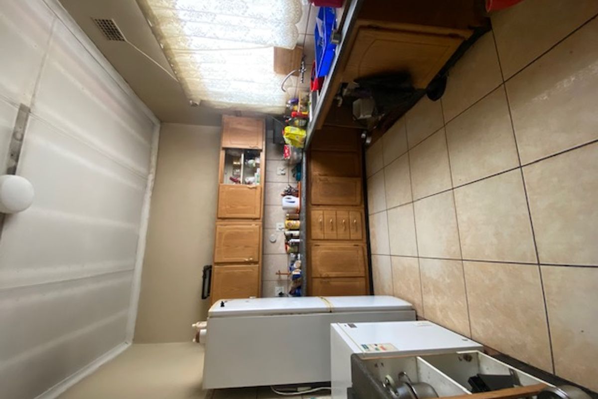 A dated kitchen featuring wooden cabinetry, tiled flooring, and a functional sink area, offering potential for modernization and renovation.