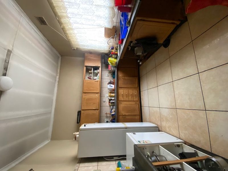 A dated kitchen featuring wooden cabinetry, tiled flooring, and a functional sink area, offering potential for modernization and renovation.