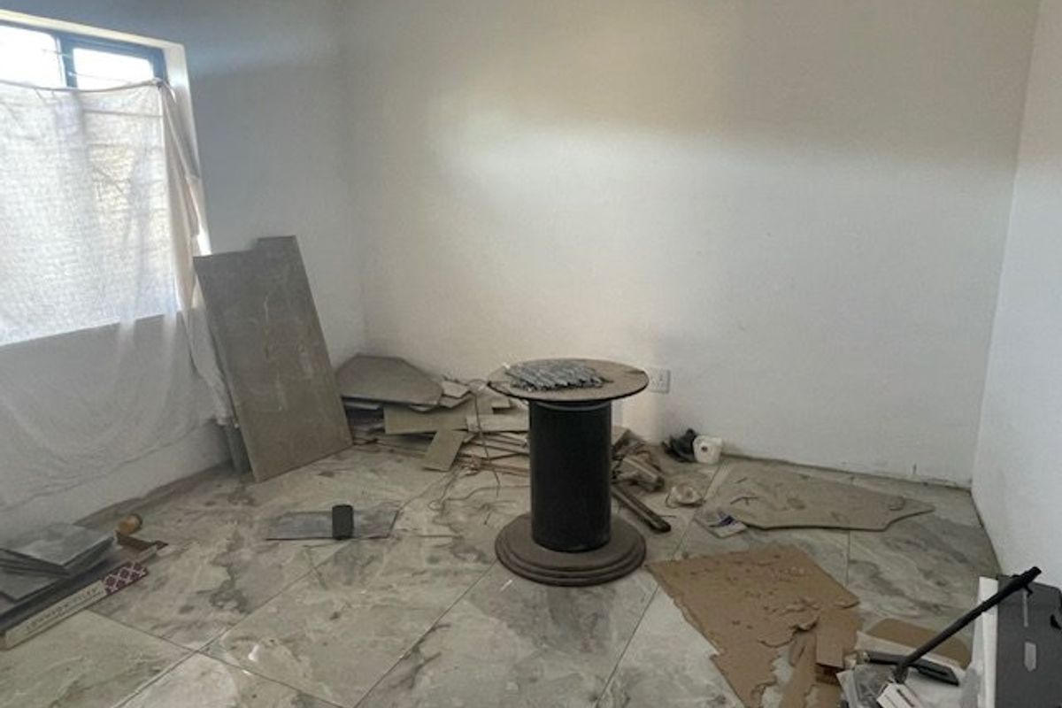 An unfinished bedroom space featuring tiled flooring, currently used for storage of construction materials and debris.