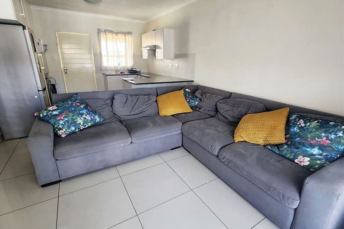 Open-plan living area featuring tiled flooring and a compact kitchen with built-in cabinetry and countertop space.