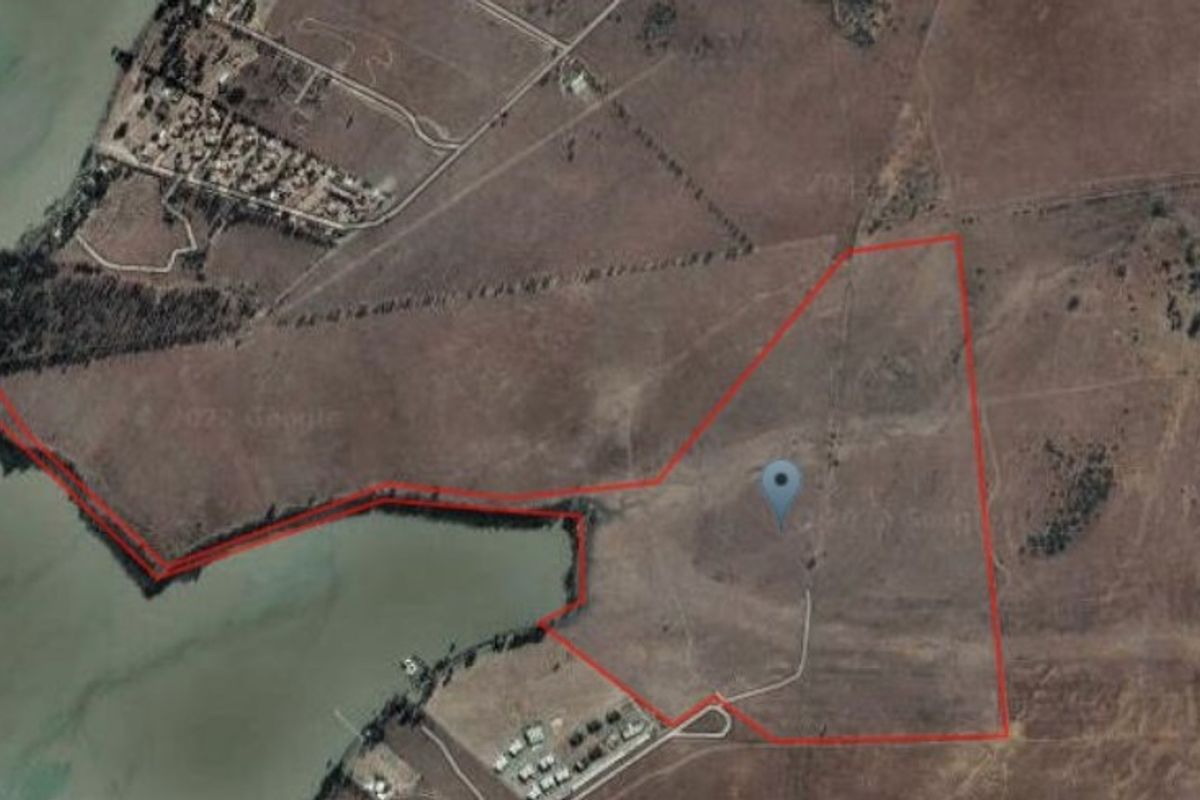 Aerial view of a large, vacant residential land parcel featuring extensive waterfront access and natural terrain.