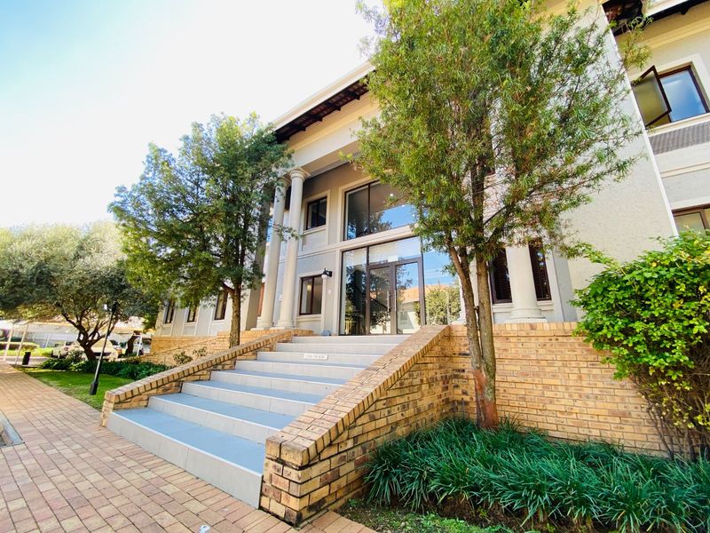 Front exterior view of a commercial building featuring a grand entrance with classical columns, a tiled staircase, and brick architectural detailing.