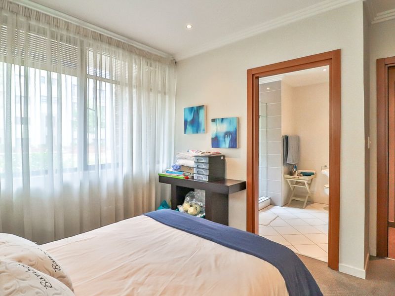 A well-maintained bedroom featuring carpeted flooring, recessed lighting, and direct access to an en-suite bathroom with tiled finishes.