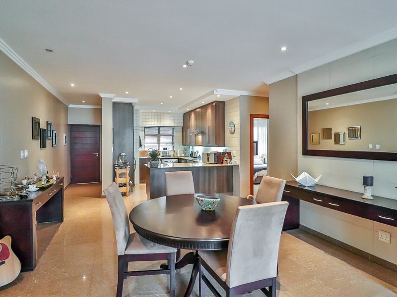 An open-plan living and dining area featuring tiled floors, recessed lighting, crown molding, and a well-appointed kitchen with built-in cabinetry.