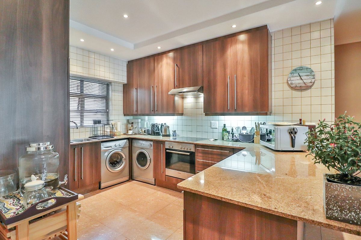 A well-appointed kitchen featuring dark wood cabinetry, granite countertops, integrated appliances, and a tiled backsplash with recessed lighting.