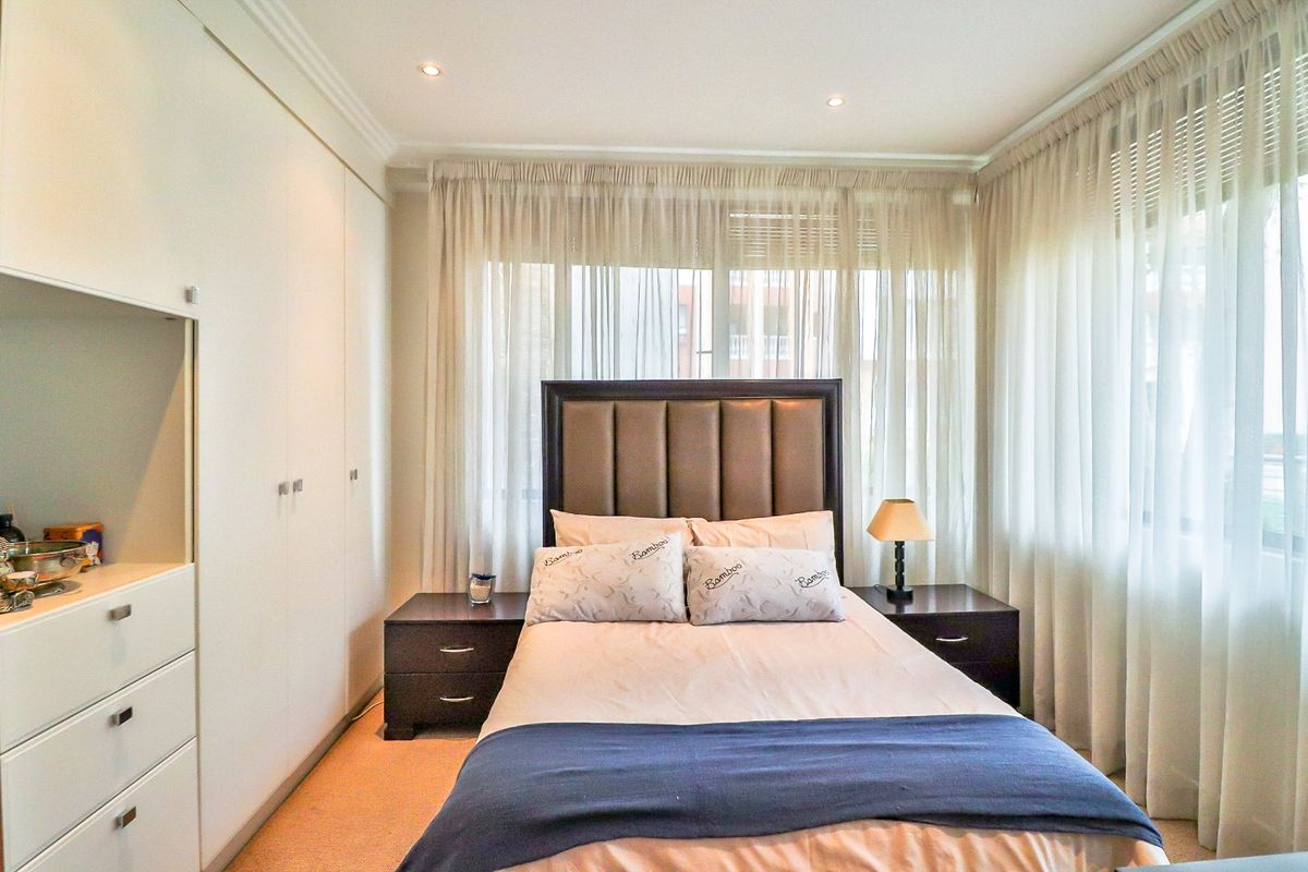 A well-maintained bedroom featuring built-in wardrobes, recessed downlighting, and neutral carpeting, offering a clean and functional living space.