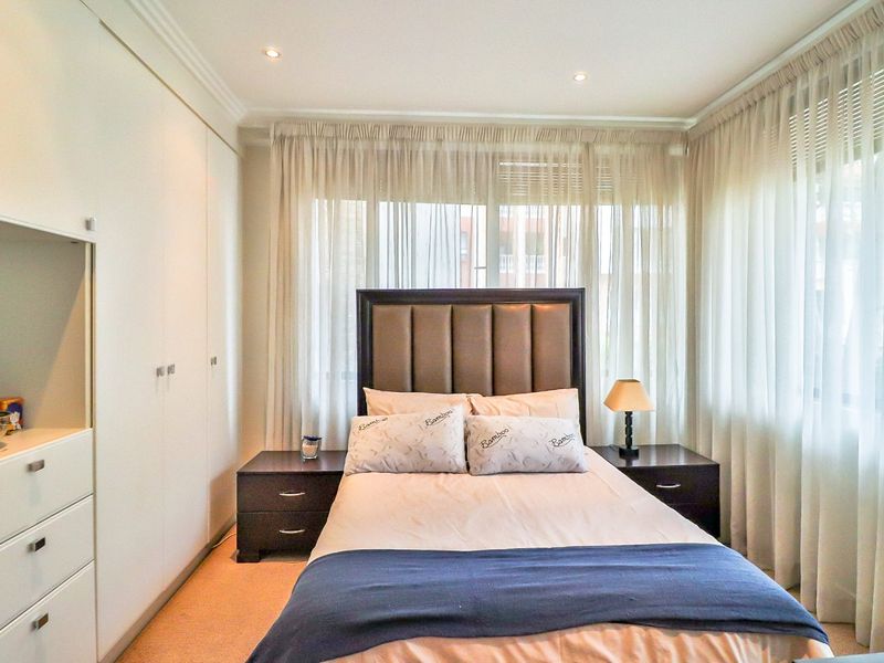A well-maintained bedroom featuring built-in wardrobes, recessed downlighting, and neutral carpeting, offering a clean and functional living space.