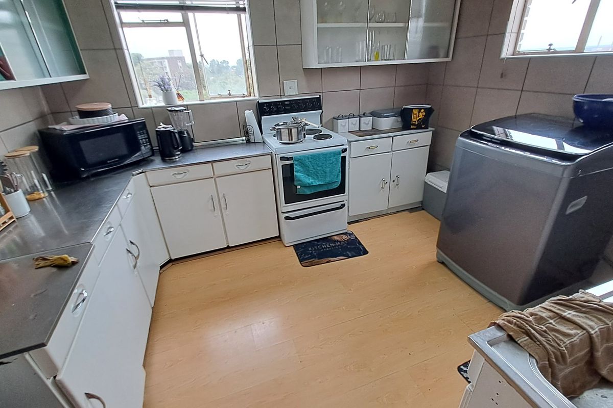 A functional kitchen featuring built-in cabinetry, stainless steel countertops, a freestanding stove, and tiled wall finishes.