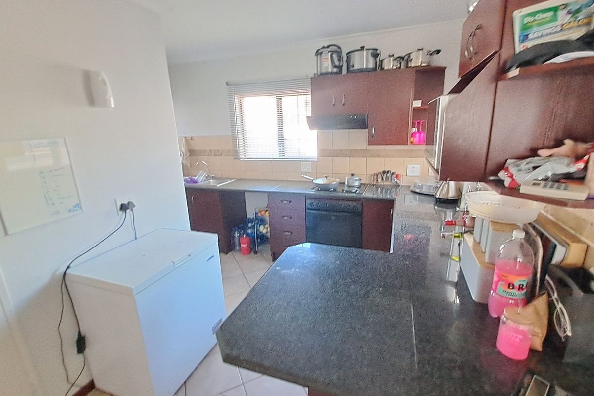 Functional kitchen featuring dark wood cabinetry, granite countertops, built-in oven and hob, and tiled flooring with a practical layout.