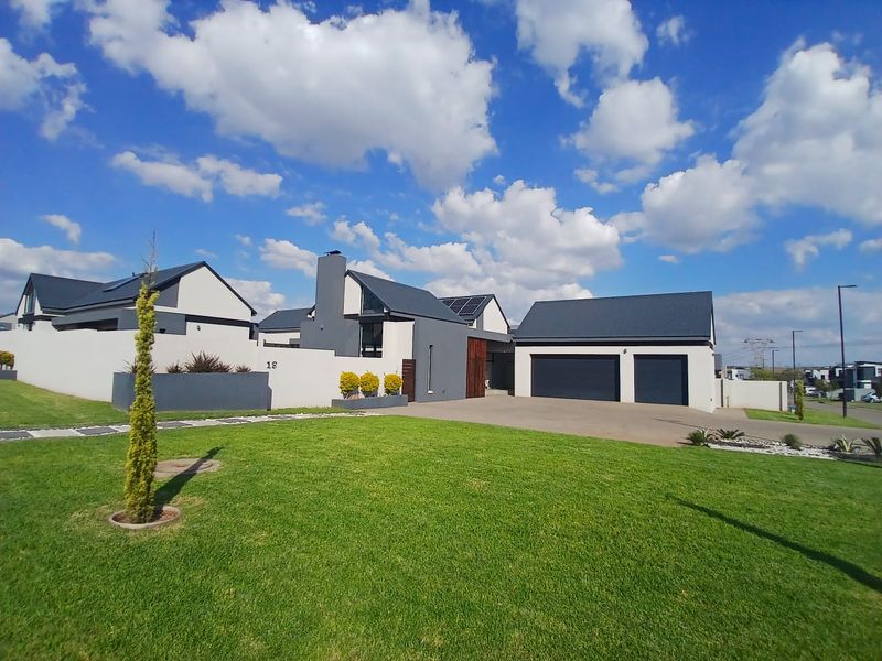 Modern contemporary house exterior featuring a double garage, paved driveway, solar panels, and a well-maintained front lawn.