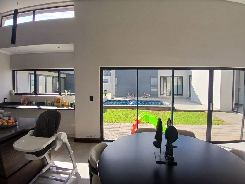 Spacious open-plan living and kitchen area featuring large sliding glass doors that provide seamless access to the rear patio and pool area.
