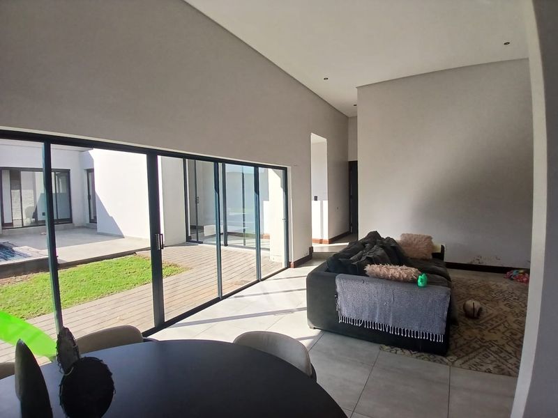 Spacious open-plan living area featuring large sliding glass doors that provide seamless access to the outdoor patio and garden area.