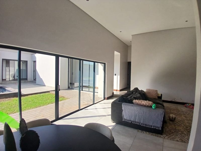 Spacious open-plan living area featuring large sliding glass doors that provide seamless access to the outdoor patio and garden area.