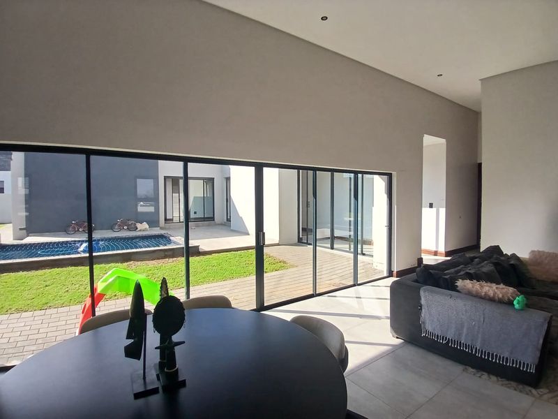 Spacious open-plan living area featuring large sliding glass doors that provide seamless indoor-outdoor flow to the patio and pool area.