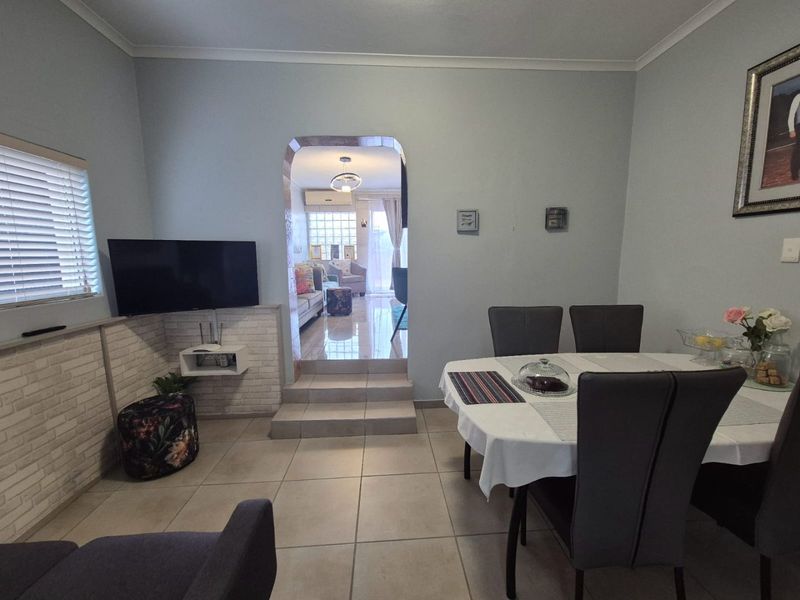 Dining area featuring tiled flooring, a decorative archway leading to an adjacent living space, and brick-style wall cladding.
