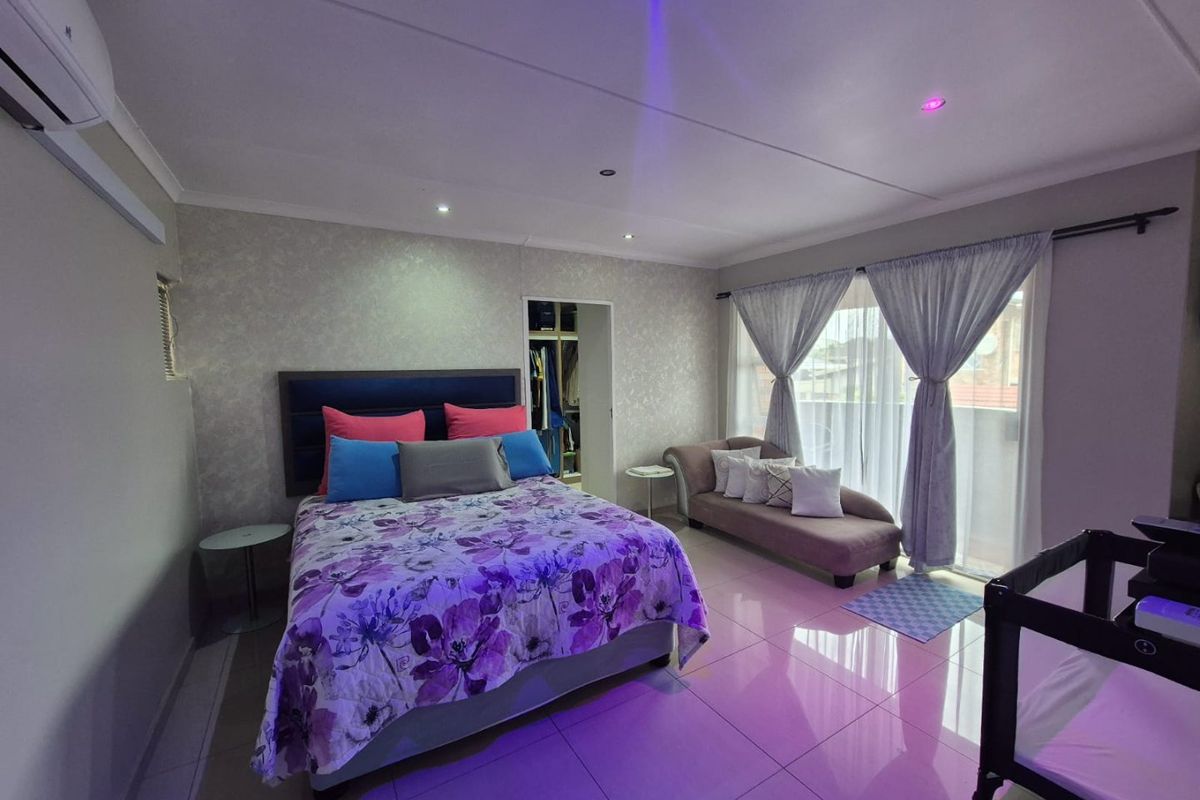 Spacious bedroom featuring tiled flooring, recessed lighting, an integrated air conditioning unit, and direct access to a balcony through sliding glass doors.