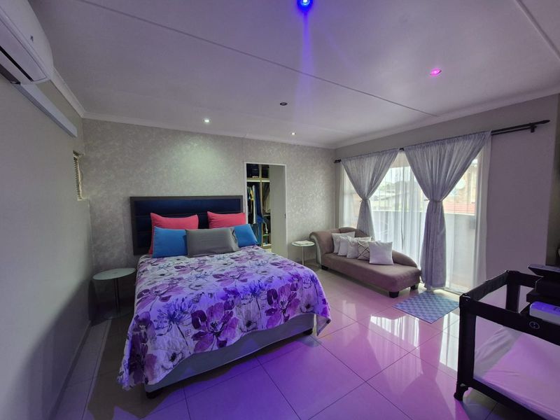 Spacious bedroom featuring tiled flooring, recessed lighting, an integrated air conditioning unit, and direct access to a balcony through sliding glass doors.