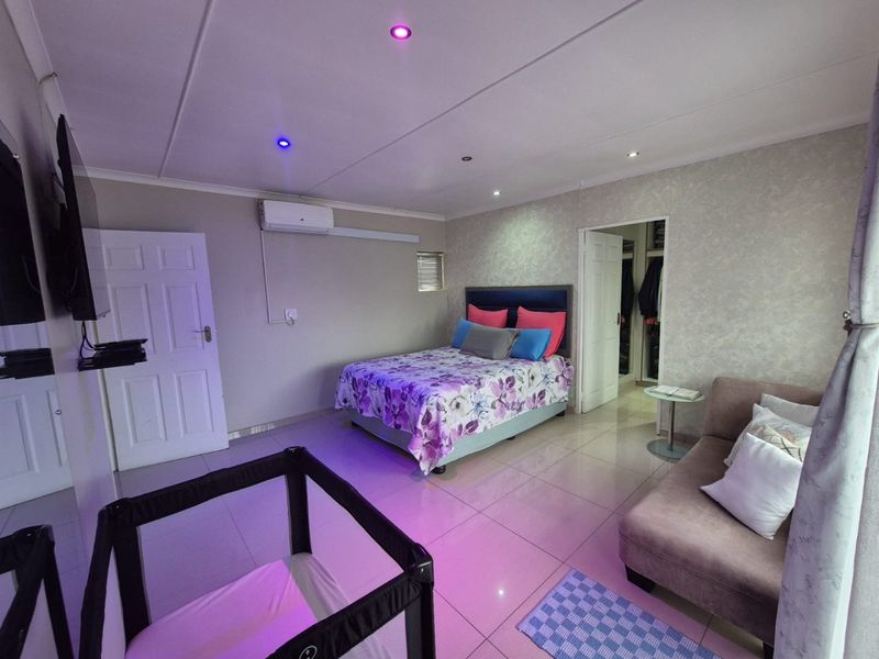 Spacious bedroom featuring tiled flooring, recessed lighting, a wall-mounted air conditioning unit, and an adjoining walk-in closet.