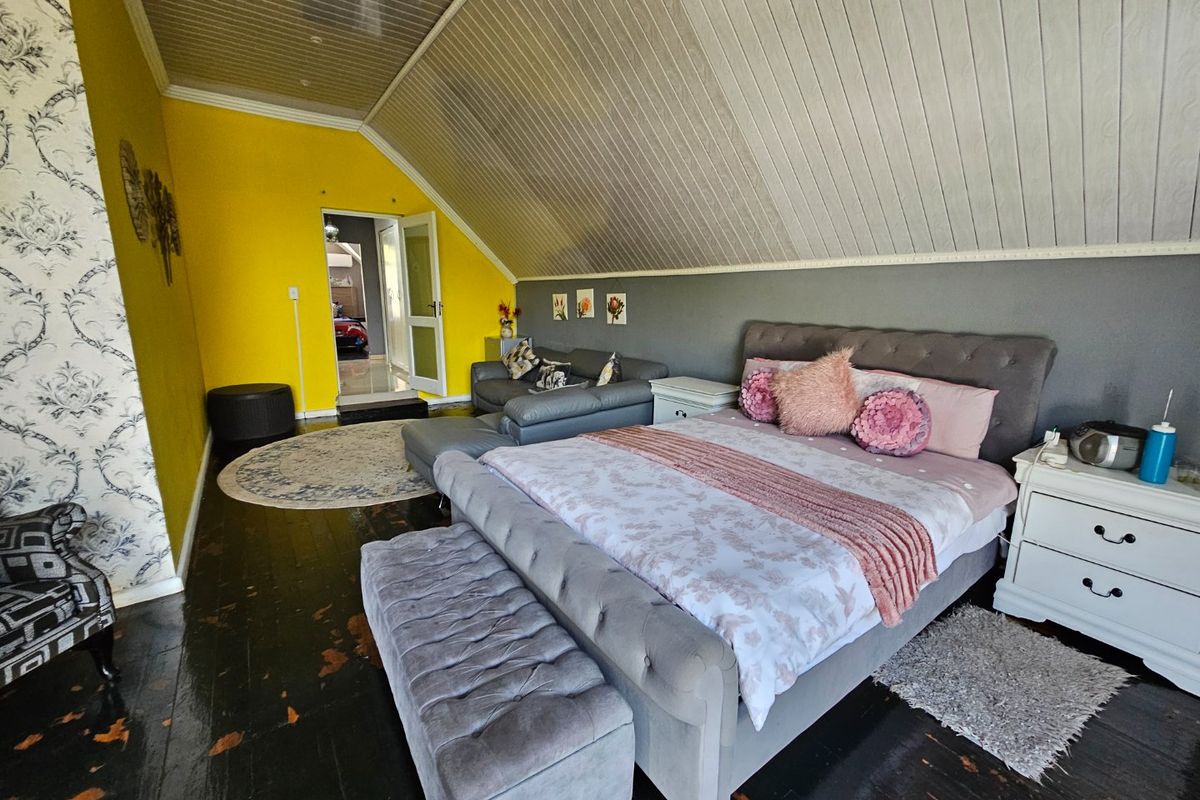 Spacious bedroom featuring a vaulted ceiling with timber paneling, bright yellow accent walls, and dark timber flooring.