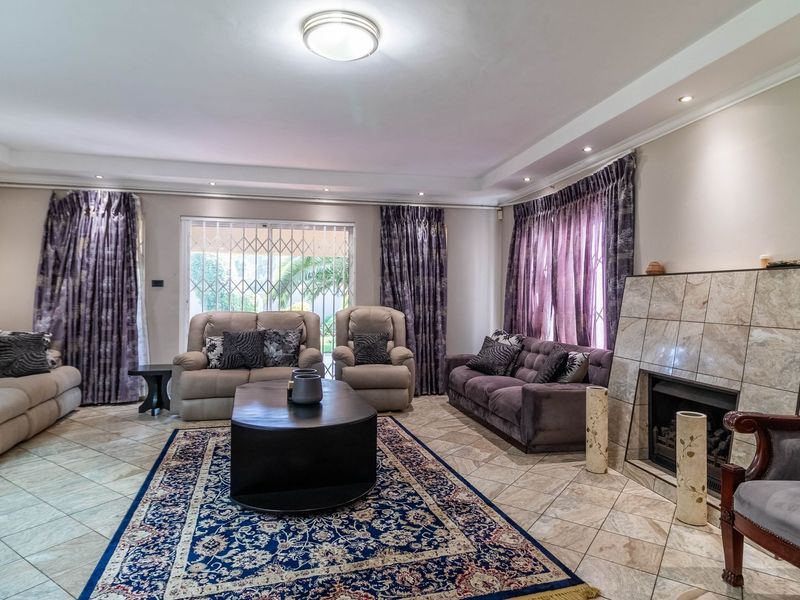 Spacious living room featuring tiled flooring, a central fireplace with a tiled surround, and recessed ceiling lighting.