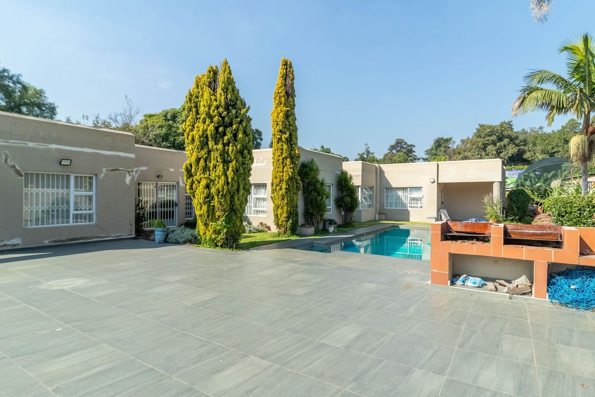Rear exterior view featuring a tiled patio, swimming pool, and a built-in brick braai area with visible wall plaster maintenance required.
