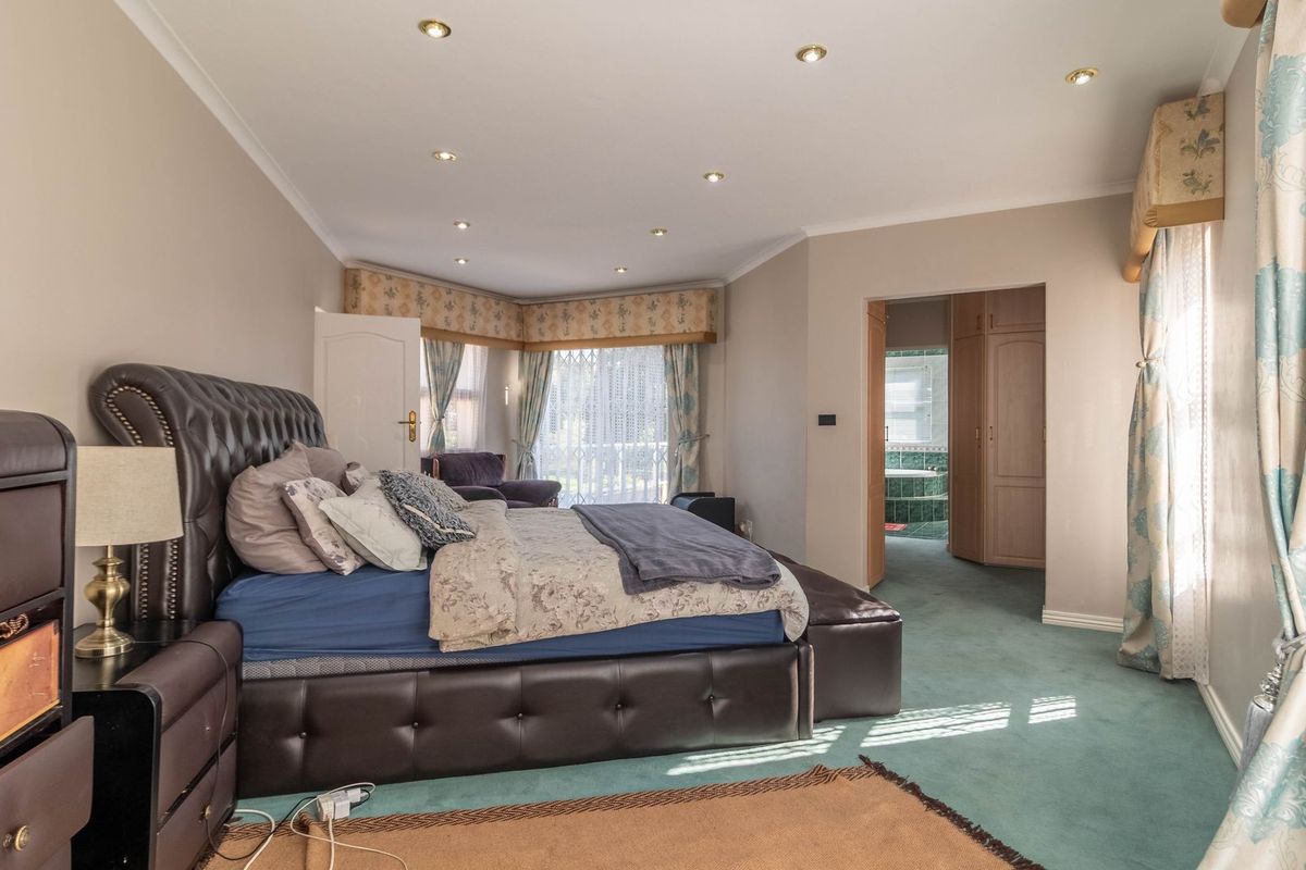 Spacious bedroom featuring recessed lighting, a bay window, and direct access to an en-suite bathroom with built-in storage cupboards.