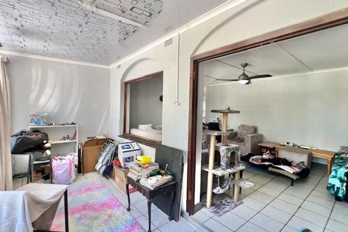 Open-plan living area featuring tiled flooring, a ceiling fan, and an interior pass-through window connecting to an adjacent space.