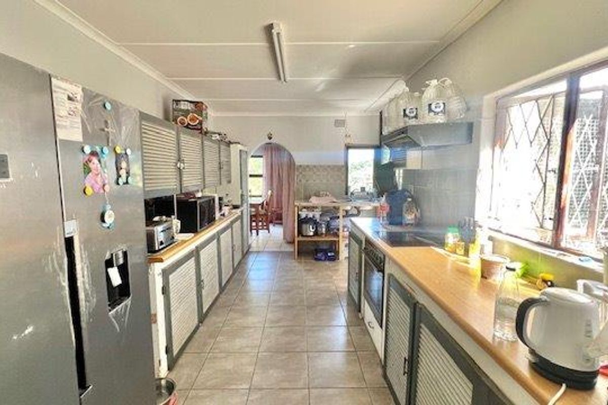 A functional kitchen featuring tiled flooring, built-in cabinetry, and integrated appliances, offering a practical layout with potential for modern updates.
