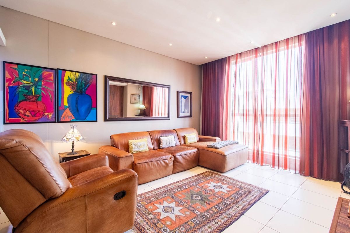 A well-lit living room featuring tiled flooring, recessed downlighting, and large windows dressed with floor-to-ceiling curtains.