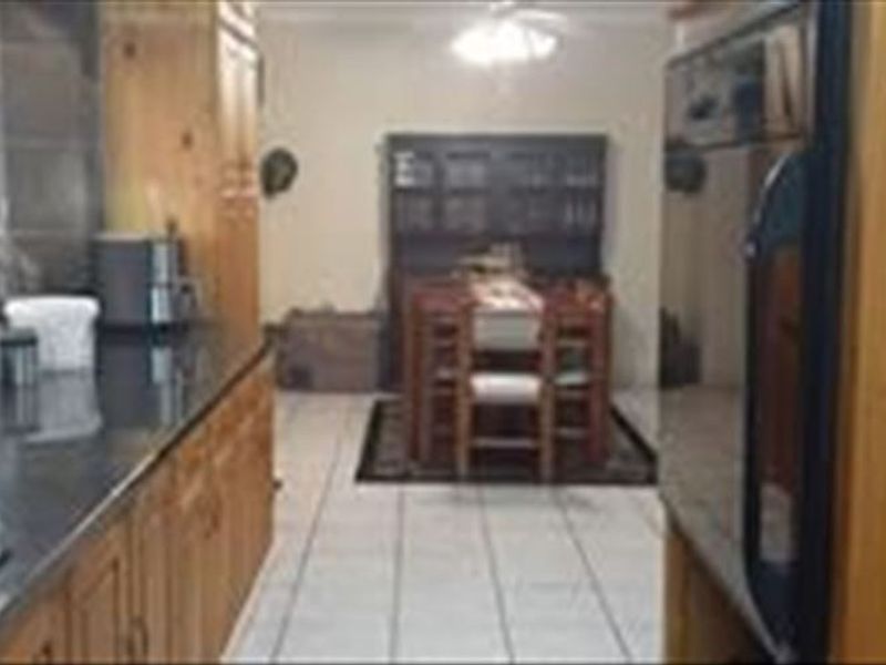 Open plan kitchen and dining area featuring timber cabinetry, dark stone countertops, and tiled flooring.