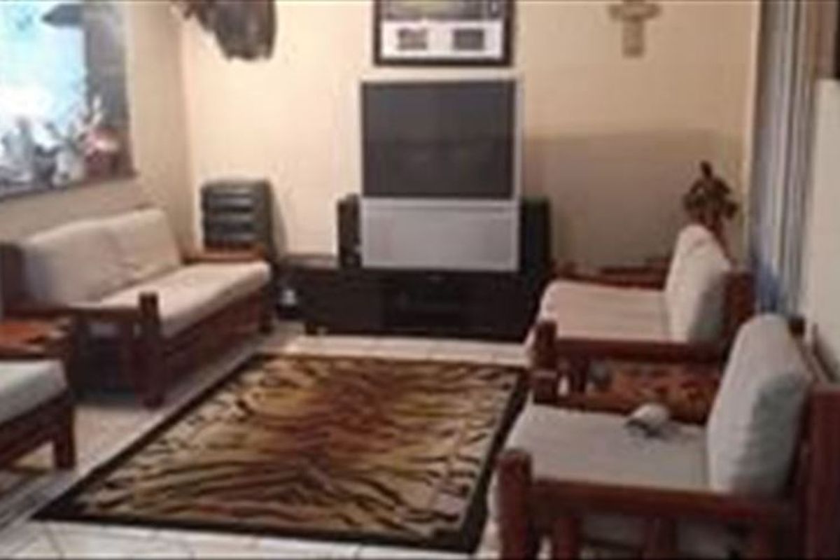 A living room area featuring tiled flooring and a pass-through window connecting to the adjacent kitchen space.