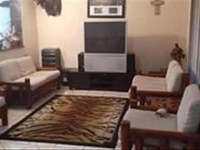 A living room area featuring tiled flooring and a pass-through window connecting to the adjacent kitchen space.