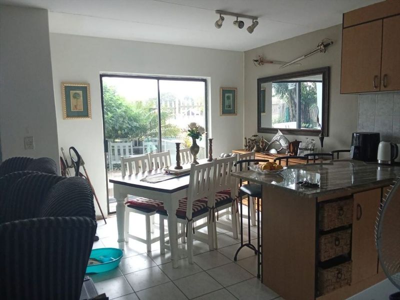 Open-plan living and dining area featuring tiled floors, granite kitchen countertops, and a sliding glass door leading to the outdoor space.