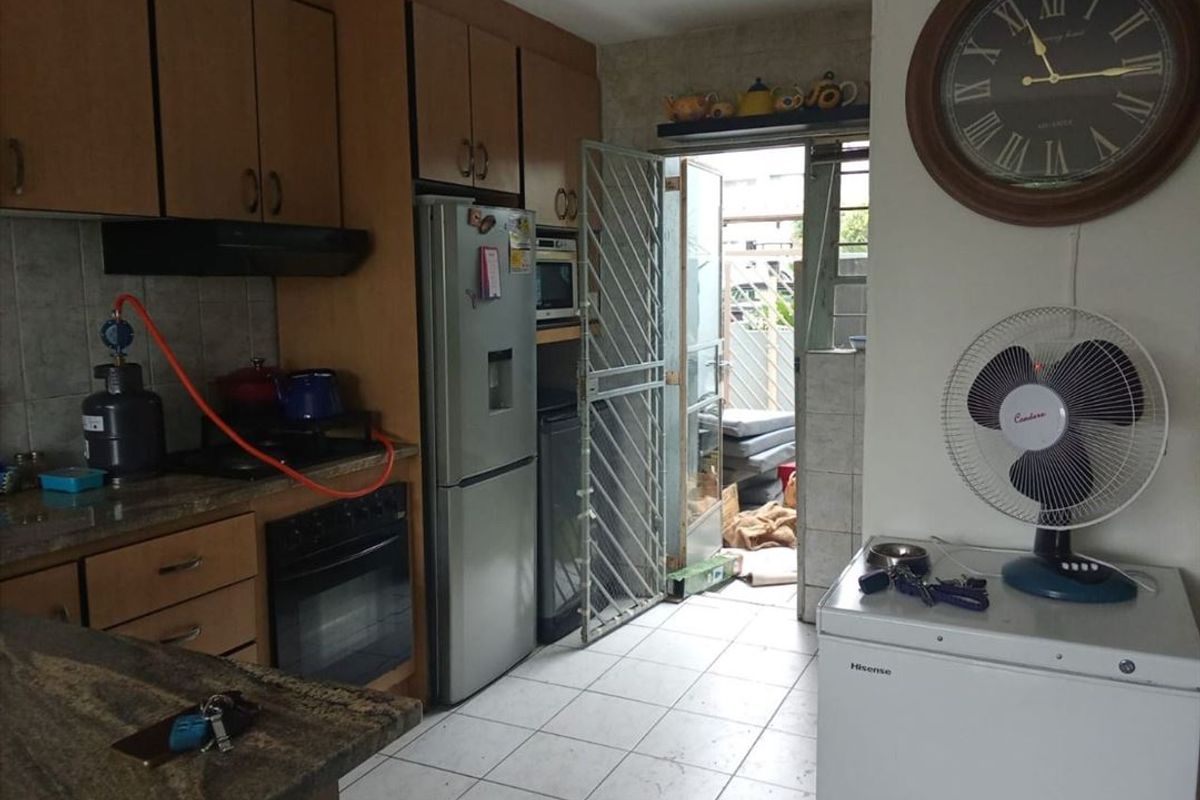 A functional kitchen featuring laminate cabinetry, granite countertops, and built-in oven, with direct access to an outdoor area through a security gate.