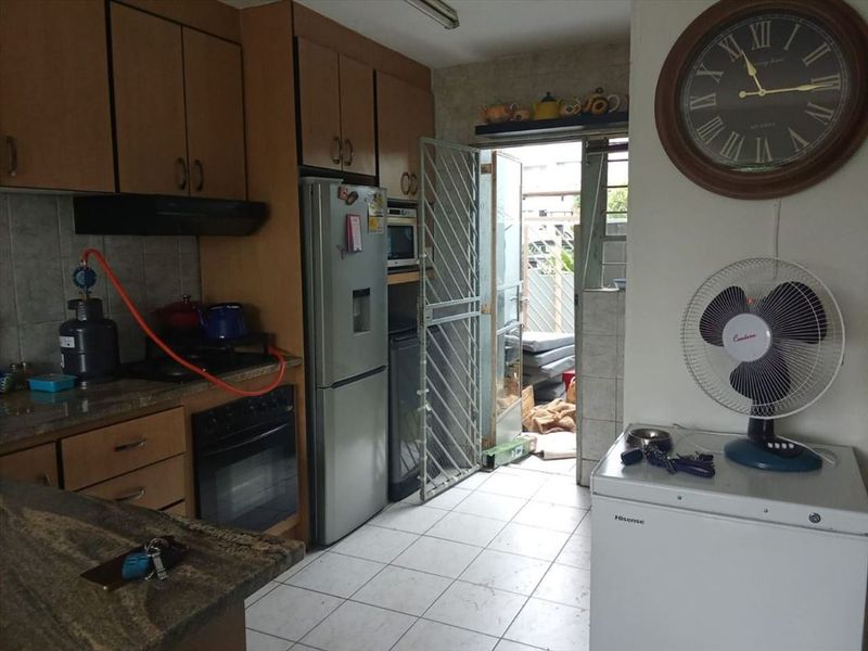 A functional kitchen featuring laminate cabinetry, granite countertops, and built-in oven, with direct access to an outdoor area through a security gate.
