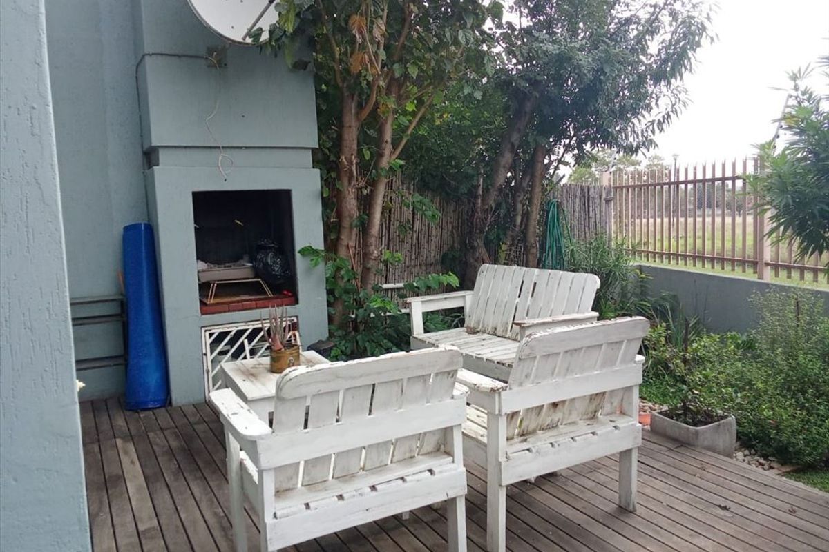 Outdoor patio area featuring timber decking and a built-in braai, providing a functional space for outdoor entertainment.