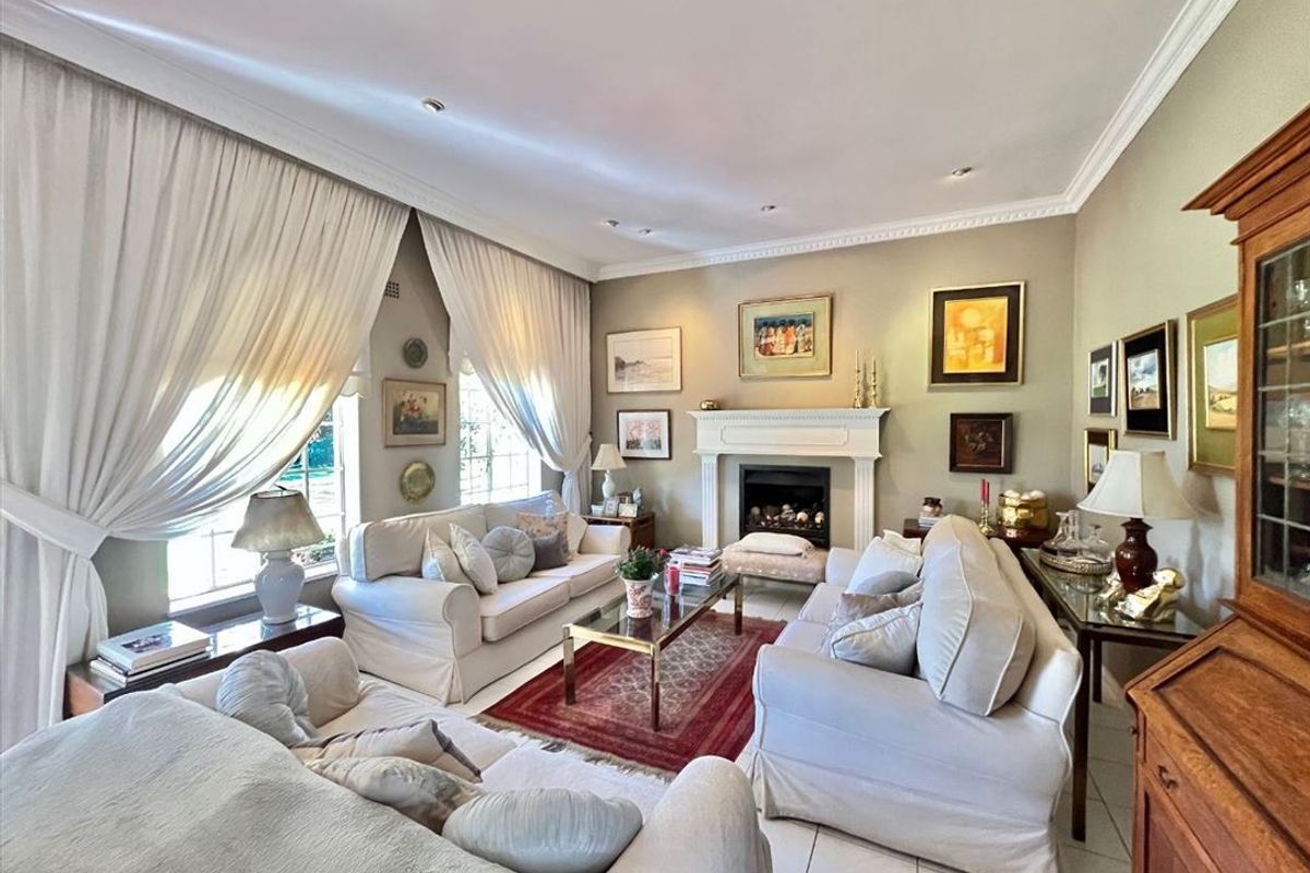 A well-maintained living room featuring a classic fireplace with a mantelpiece, crown molding, recessed lighting, and neutral tiled flooring.