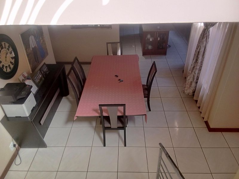 A dining area featuring tiled flooring, viewed from an elevated position, providing a clear view of the floor layout and adjacent space.
