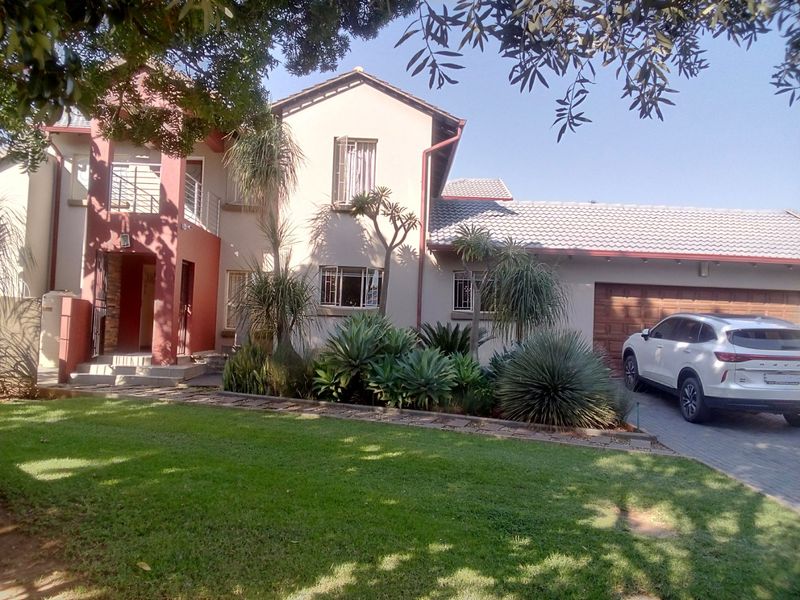 Front elevation of a double-story house featuring a paved driveway, double garage, balcony, and established garden.