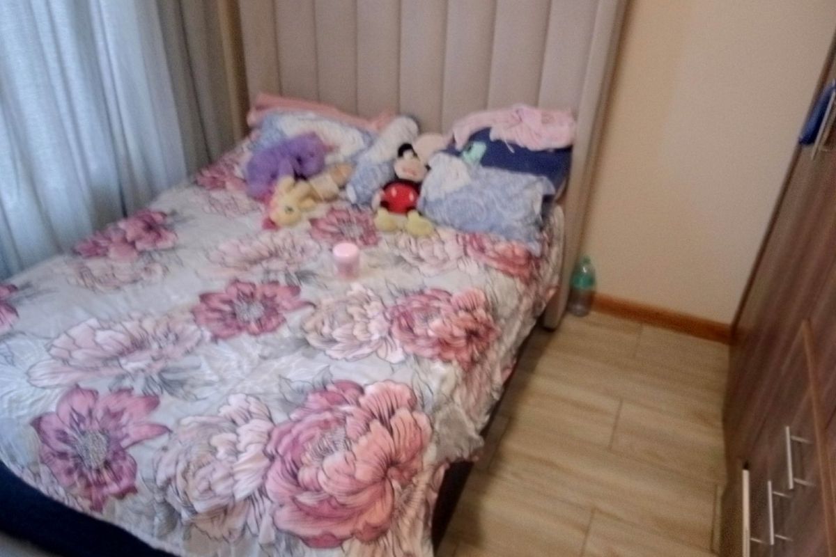 A bedroom featuring laminate flooring, an upholstered headboard, and a built-in wardrobe.